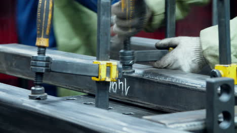 Mann-In-Handschuhen-Legt-Metallrohling-Auf-Spezialbehandlungstisch.-Schraubzwinge