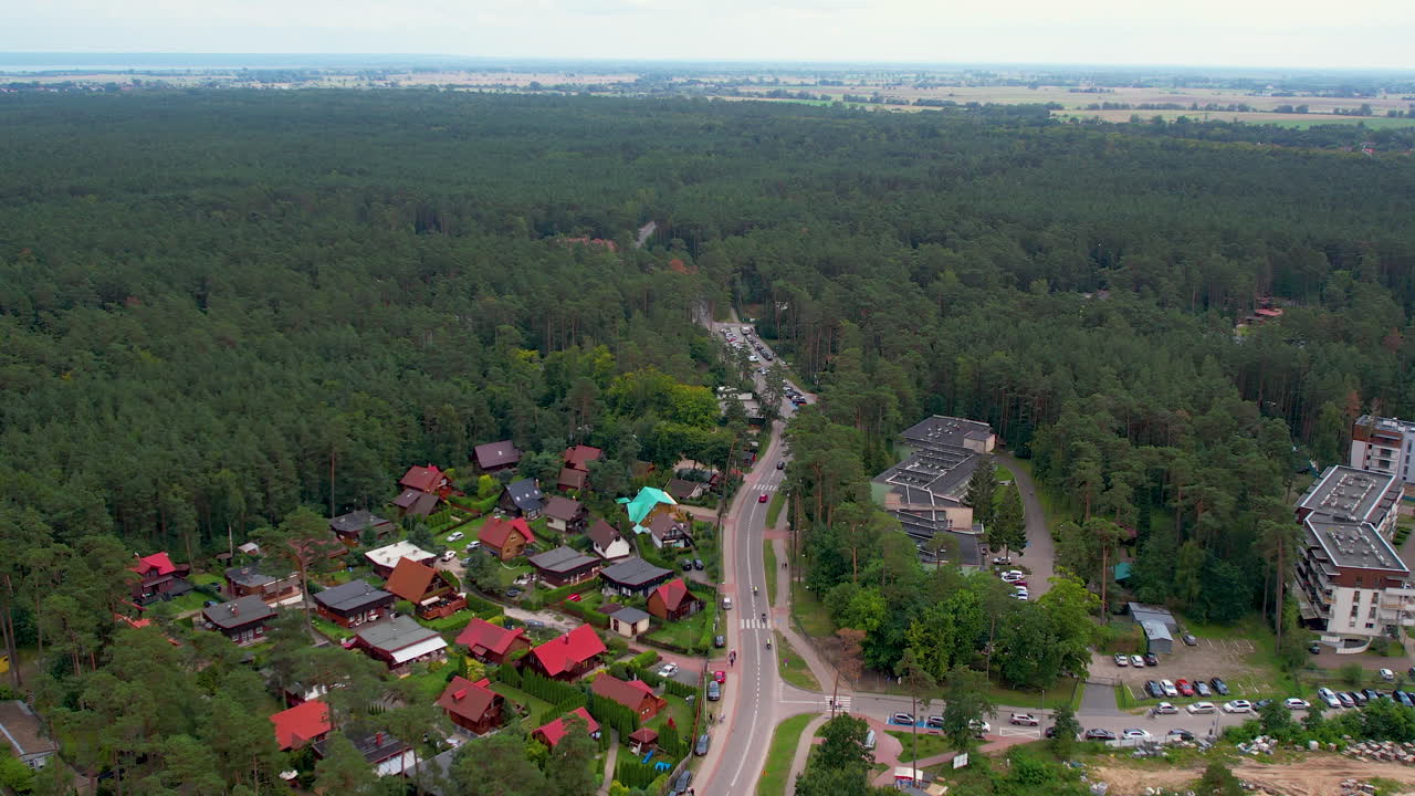 Samochody jadące drogą wzdłuż hoteli, apartamentów i lasu w Stegnie, Polska.