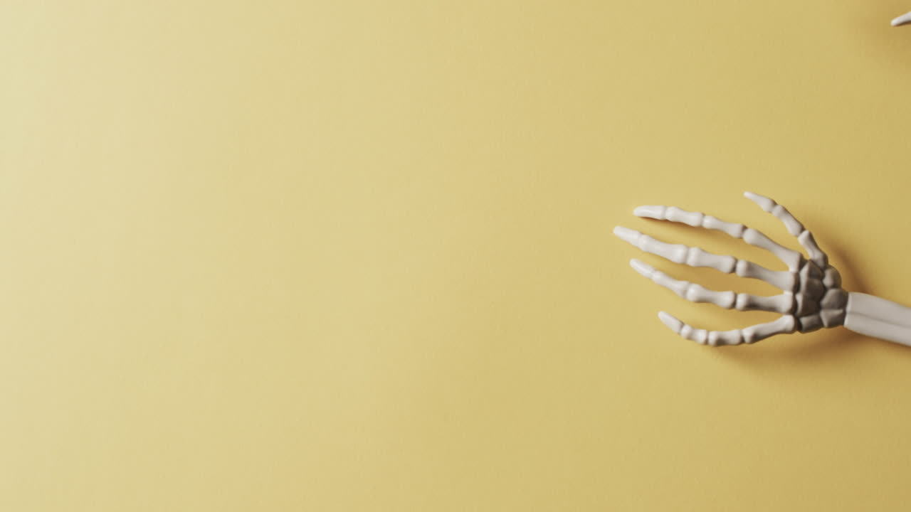 노란색 배경에 복사 공간과 함께 할로윈 골격 손의 비디오