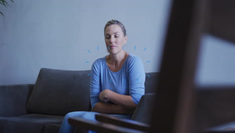 sitting on sofa, woman in blue shirt appearing thoughtful and relaxed