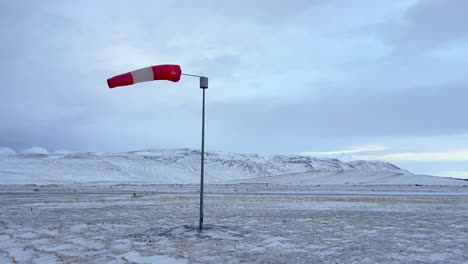 wind sock moving in the wind on a frozen airport in iceland with in the background in snow covered landscape