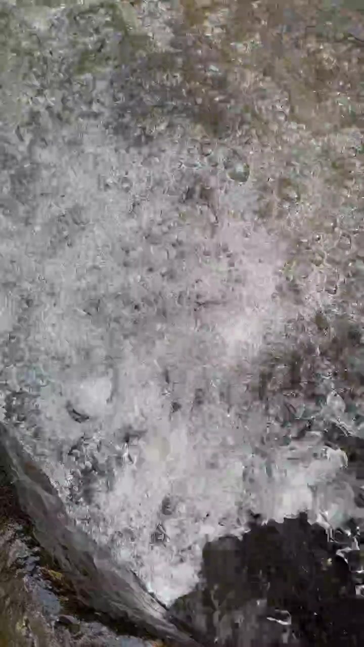 Primer plano de agua cristalina fluyendo sobre rocas en un arroyo