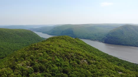 Aerial-shot-overlooking-rolling-mountains-and-beautiful-clear-blue-sky-along-the-river