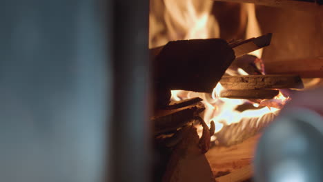 close up of wood burning in fireplace as flames rise and flicker between stacked logs, fire glows brightly, illuminating wooden textures with soft light and creating warm, rustic indoor atmosphere