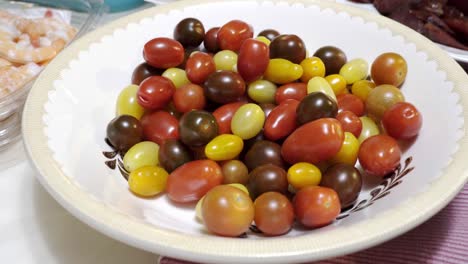 una mano agarra un tomate cherry de un plato de tomates cherry mixtos en 4k