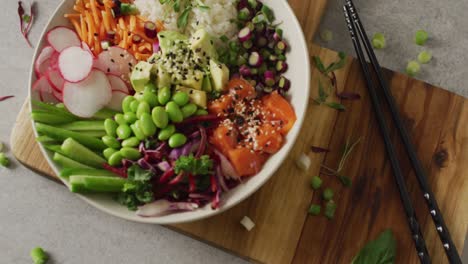 Composition-of-bowl-of-rice-and-vegetables-with-chopsticks-on-white-background