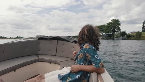 Young-male-sitting-in-luxurious-boat-watching-the-waters-and-dutch-rural-area