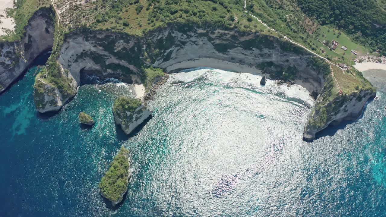 Aerial drone shot reveals the pristine white sands, dramatic towering limestone cliffs, and the vibrant turquoise water of Diamond Beach on Nusa Penida island, Bali, Indonesia