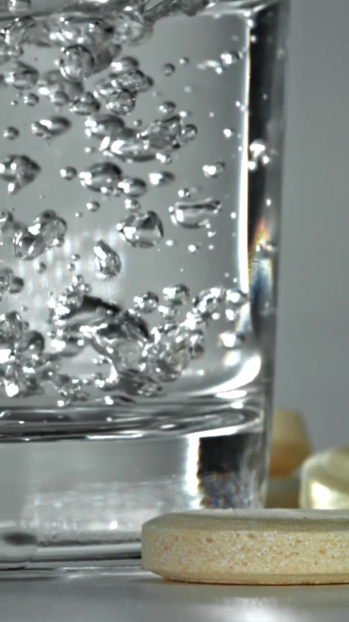 Primo piano di bolle che salgono in un bicchiere d'acqua con una compressa effervescente