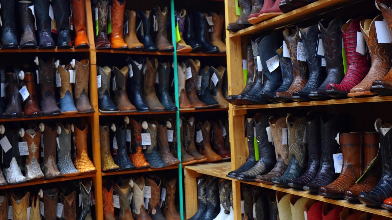 Chicago, USA, 7. Mai 2026: Regale mit exotischen Leder-Cowboystiefeln in einem Westernladen. Holzfächer gefüllt mit Krokodil- und Schlangenhautpaaren in Erd- und tiefen Farben.