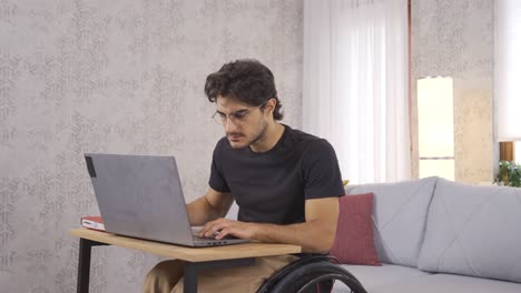 un joven discapacitado trabajando duro con una computadora portátil.