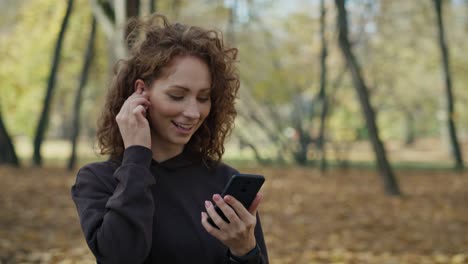 Mujer-Pelirroja-Sonriente-Caminando-Por-El-Parque-Y-Enviando-Mensajes-De-Texto