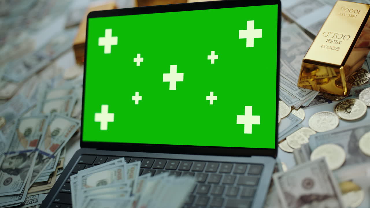 Laptop with Green Screen Surrounded by Money and Gold