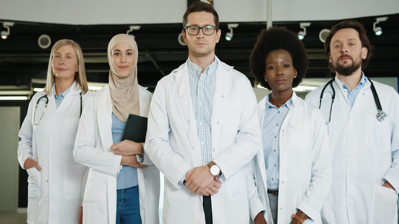 Multiethnic doctors team in medical coats standing in hospital lab and looking at camera