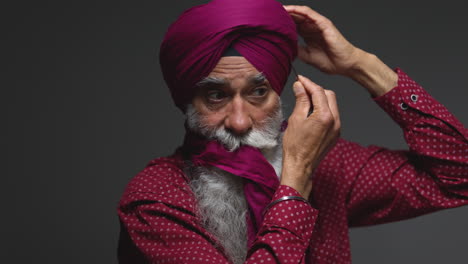 Close-Up-Low-Key-Studio-Lighting-Shot-Of-Senior-Sikh-Man-With-Beard-Using-Salai-Needle-When-Putting-On-Turban-Against-Dark-Background-Shot-In-Real-Time