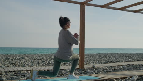 mujer haciendo lunges en la playa