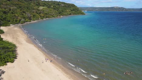 4k aerial drone flyover tourists on scenic tropical beach in costa rica