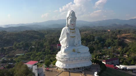 aéreo dando vueltas alrededor de wat huay pla kang gigante estatua blanca grande y templo de pagoda con montañas y espacio terrestre en chiang rai, tailandia