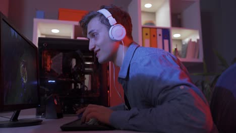 young man is playing video games on his computer and is happy.