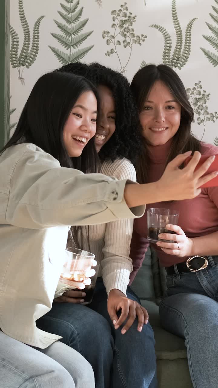 Happy female friends taking selfie at home during weekend party