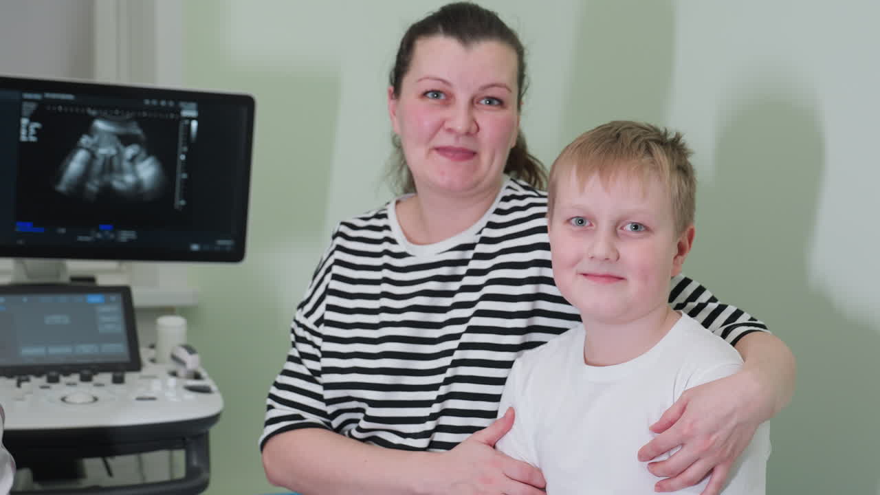 Mother and child seated on hospital bed, mother holding child firmly while both smile joyfully, depicting a caring family moment in a medical setting with ultrasound in the background