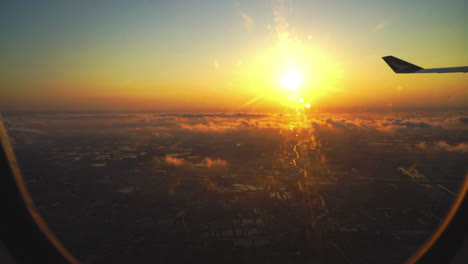 sonnenaufgang mit blick auf die stadt aus dem flugzeugfenster