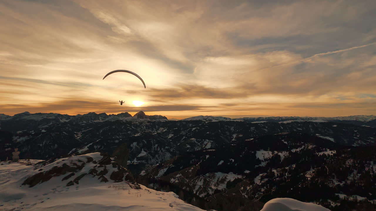 Paragliding over Snowy Mountain Peaks at Sunset