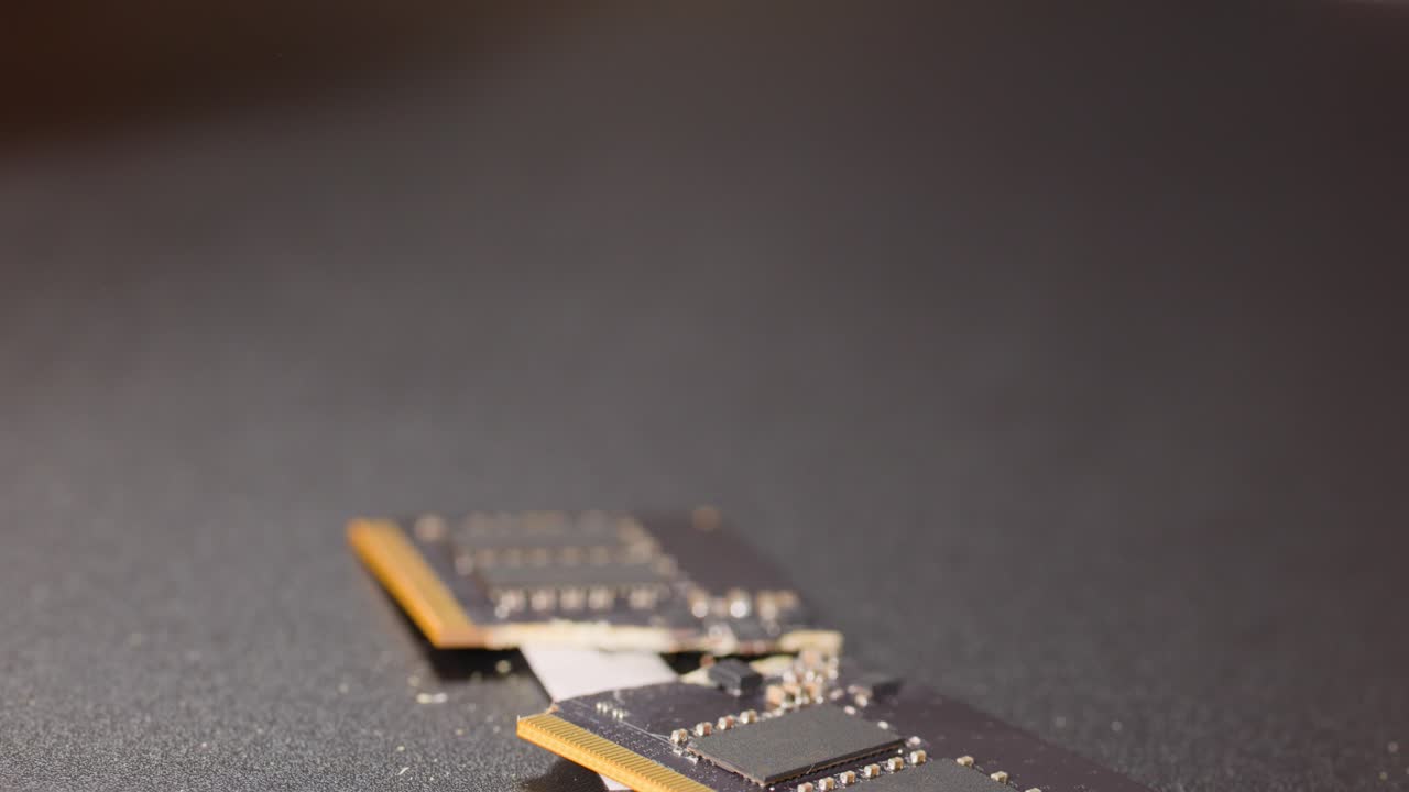 Close-up shot of hands snapping a computer memory module in half over a dark surface
