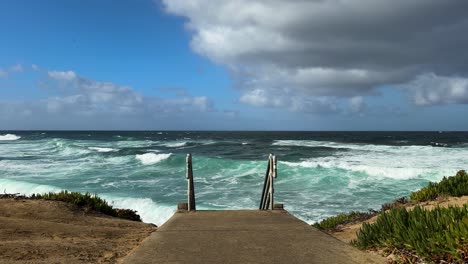 Escaleras-Que-Conducen-Al-Océano-En-Un-Hermoso-Día-Con-Olas-Y-Agua-Verde-Azul