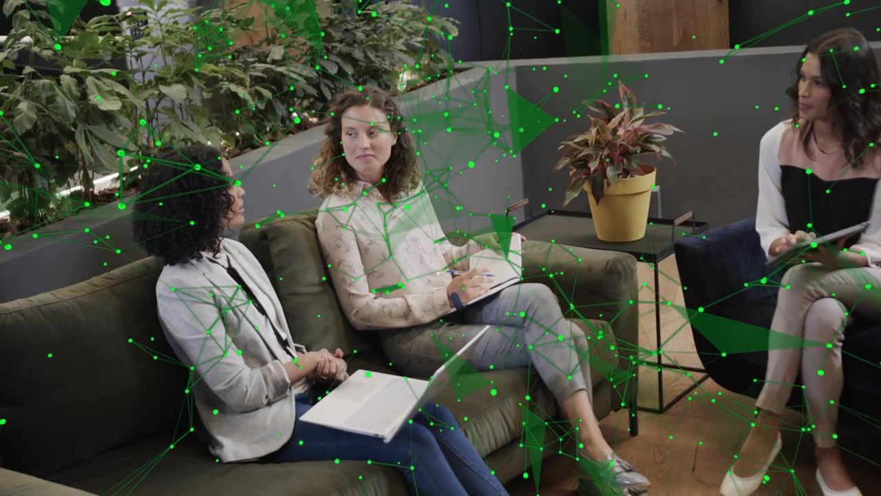 Donna a destra che tocca un tablet, donne sul divano che prendono appunti, condividendo idee di business con una sovrapposizione verde in movimento