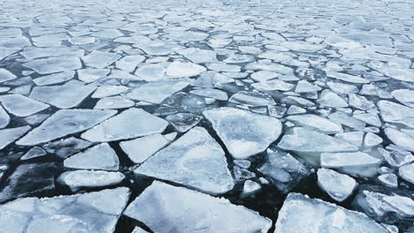 Drone-shot-panning-around-showing-huge-chunks-of-frozen-ice-in-Lake-Michigan,-flying-fast-foward