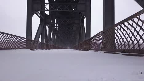 Snow-level-view:-Damaged-old-steel-truss-bridge-deck,-cold-winter-day