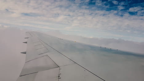 view of an airplane wing as it ascends above the clouds