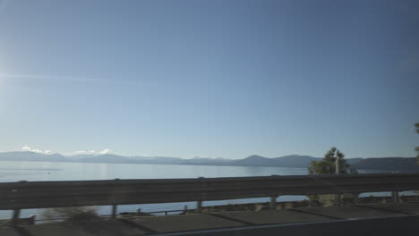 Lake-Tahoe-passes-by-beyond-the-guard-rail-on-the-side-of-the-road-from-the-driver-side-POV