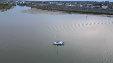 Yacht-with-sails-down-on-calm-water-at-dusk-on-the-River-Wyre-Estuary-Fleetwood-Lancashire-UK