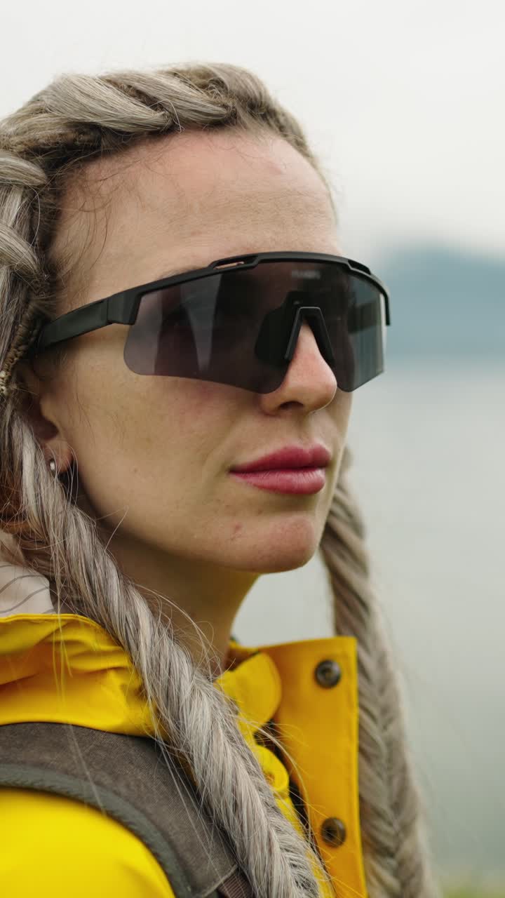 Pensive Woman with Braids in Sunglasses and Yellow Raincoat Outdoors