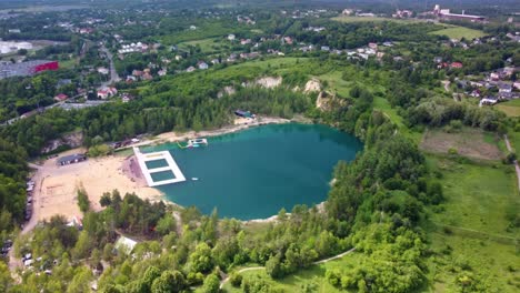 Aerial-view-of-natural-swimming-pool-Balaton-with-surrounding-greenery-and-nearby-houses-in-Poland