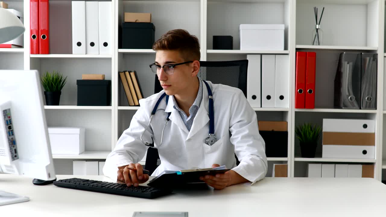 Young doctor working with documents at computer