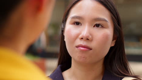 close up of two smiling young female friends meeting and talking in urban setting together 3