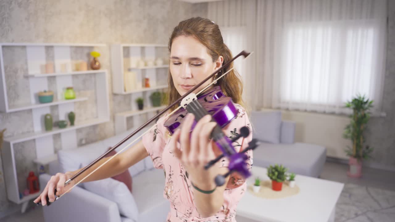 una joven violinista tocando su violín púrpura en casa.