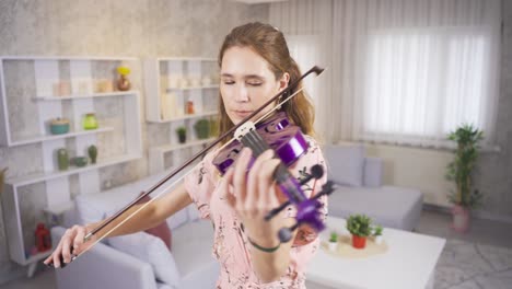 violinist young woman playing her purple violin at home.