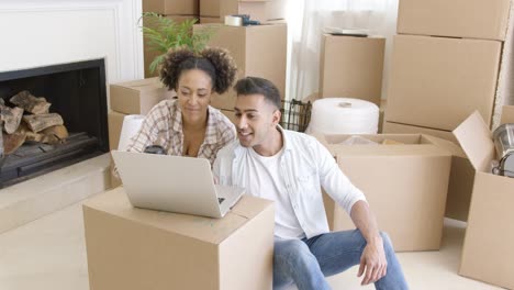 happy couple using laptop in their new apartment