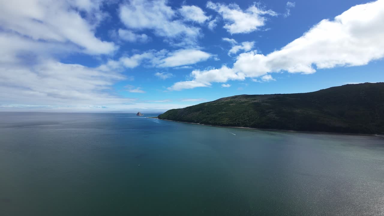 Experience breathtaking scenery of a tranquil coastline under a vibrant sky filled with clouds