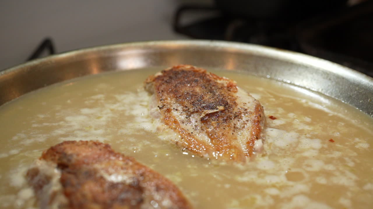 스토브 위에 있는 프라이팬에 홈메이드 짭짤한 소스에 끓인 뼈 없는 닭 가슴살 - 돌리 백 슬로우 모션