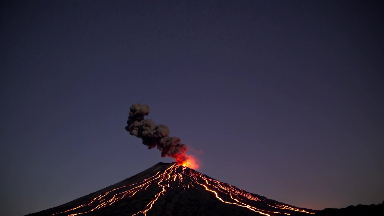 Vulcano attivo in eruzione con lava incandescente che scorre di notte