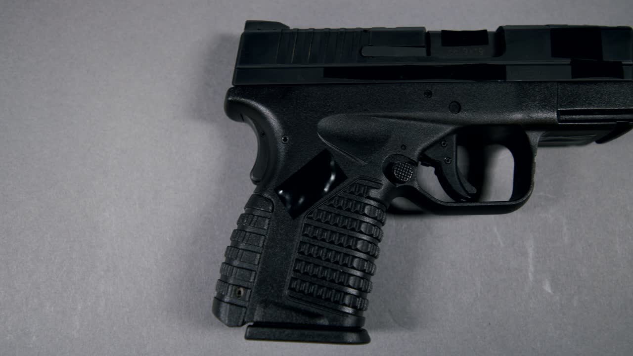 black Semi-Automatic 9mm Handgun on gray background, right hand side view, slow pan left to right, 4k