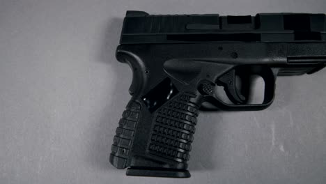 black semi-automatic 9mm handgun on gray background, right hand side view, slow pan left to right, 4k