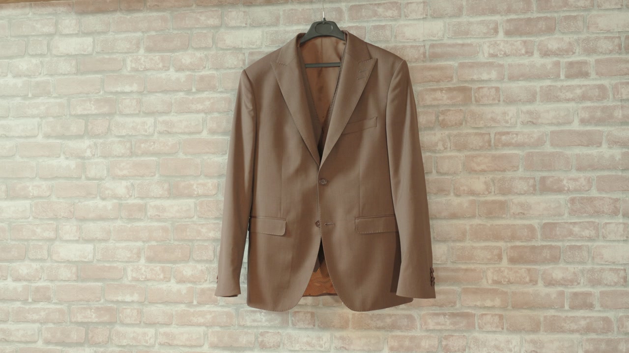 orbiting shot of a grooms wedding suit hanging on display before the wedding