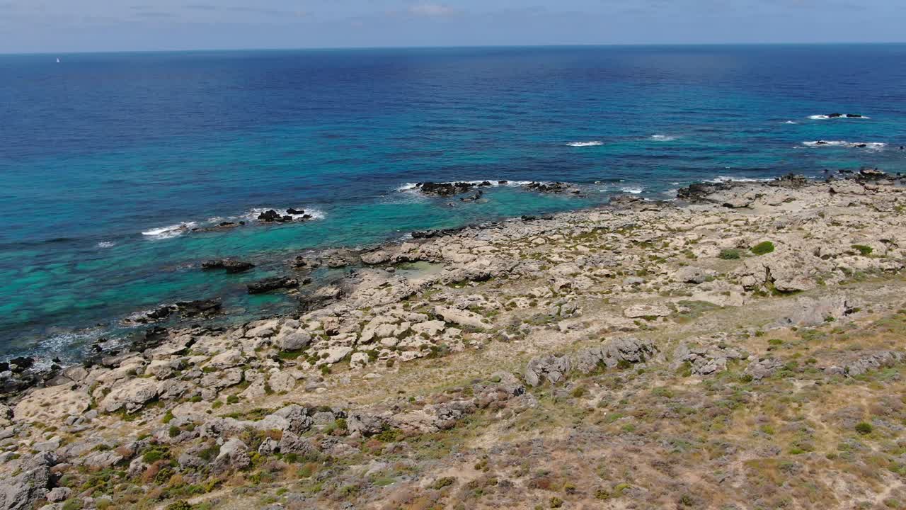Elafonissi Beach peninsula in Crete Greece with cross grave on the western cape rocks, Aerial dolly in shot