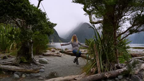 Girl-on-a-Milford-Sound-swings-against-the-misty-mountains-in-the-distance